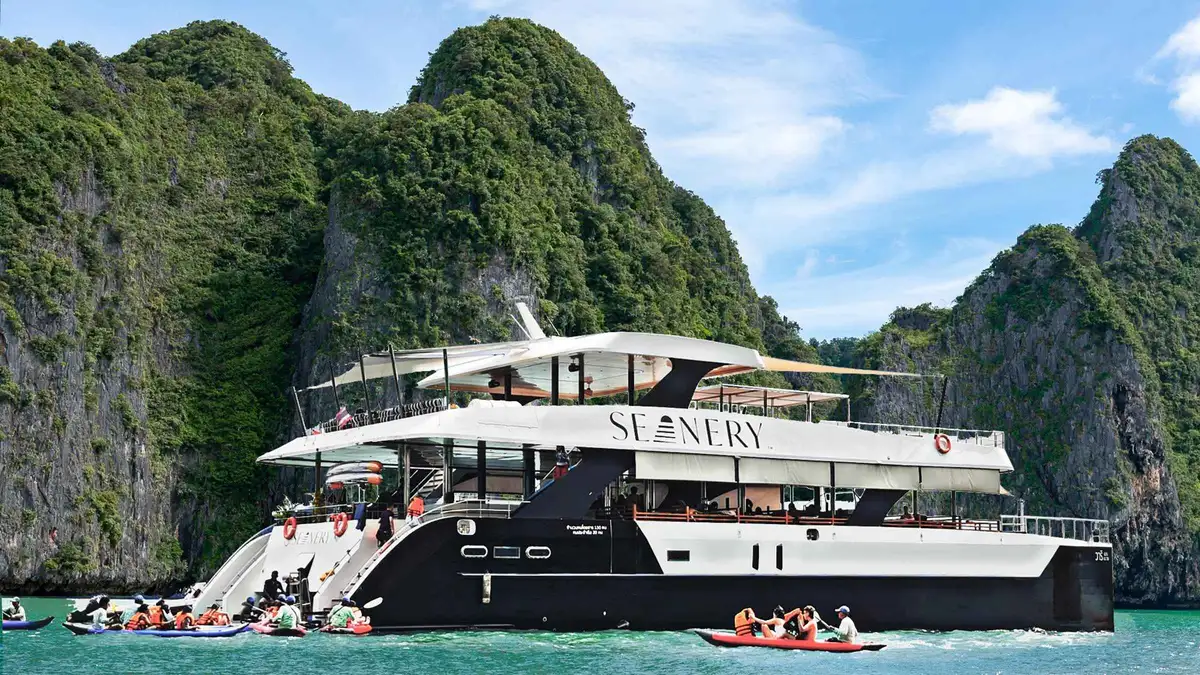 Catamaran with day beds anchored under limestone cliffs at sunset on a James Bond Island Phuket boat tour in Phang Nga Bay, Thailand