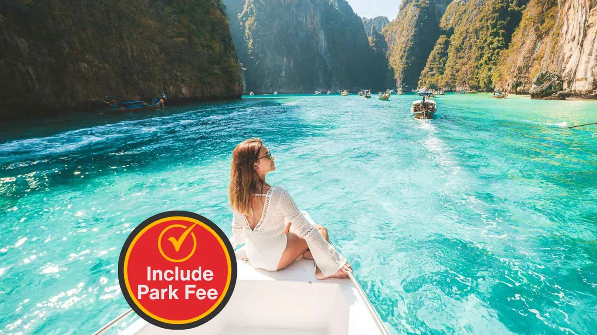 Snorkellers in life jackets in clear water beside limestone cliffs at Phi Phi Leh on a Phuket boat tour with park fees included, Thailand