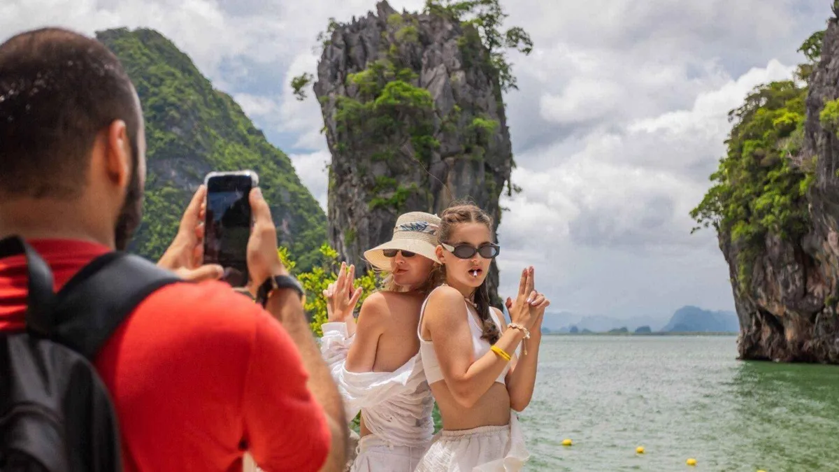 Sea canoe passing under a limestone overhang at Panak Island on a 6-island Phang Nga Bay Phuket boat tour, Thailand